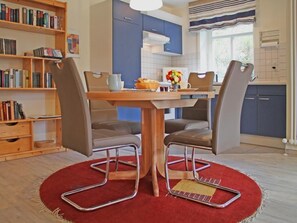 Ein Essbereich mit einem Holztisch, vier Stühlen und einem roten Teppich.