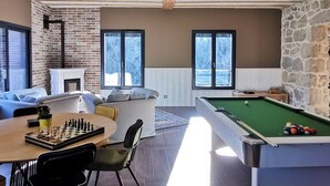 Una habitación acogedora con chimenea, mesa de billar y mesa de ajedrez.