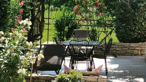 An outdoor patio with a table and chairs, surrounded by lush greenery and flowering plants. - A l'Isle sur la Sorgue, charme provençal (L'Isle-sur-la-Sorgue)