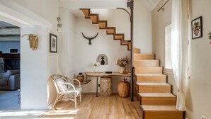 A modern interior with a wooden staircase, a white wall with a bull's head decoration, a wicker chair, and a small table with a vase of flowers. - A l'Isle sur la Sorgue, charme provençal (L'Isle-sur-la-Sorgue)