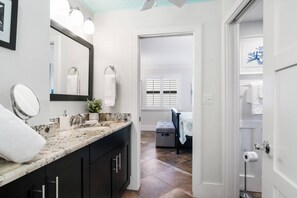 A modern bathroom with a marble countertop, a large mirror, and a walk-in shower.