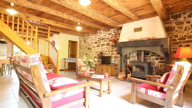 A cozy living room with a stone wall, wooden beams, a fireplace, and a staircase. - Charming 19th-Century Farmhouse near Loire Gorges, Cozy Interior, Baby Equipment, Optional Services (Aurec-sur-Loire)
