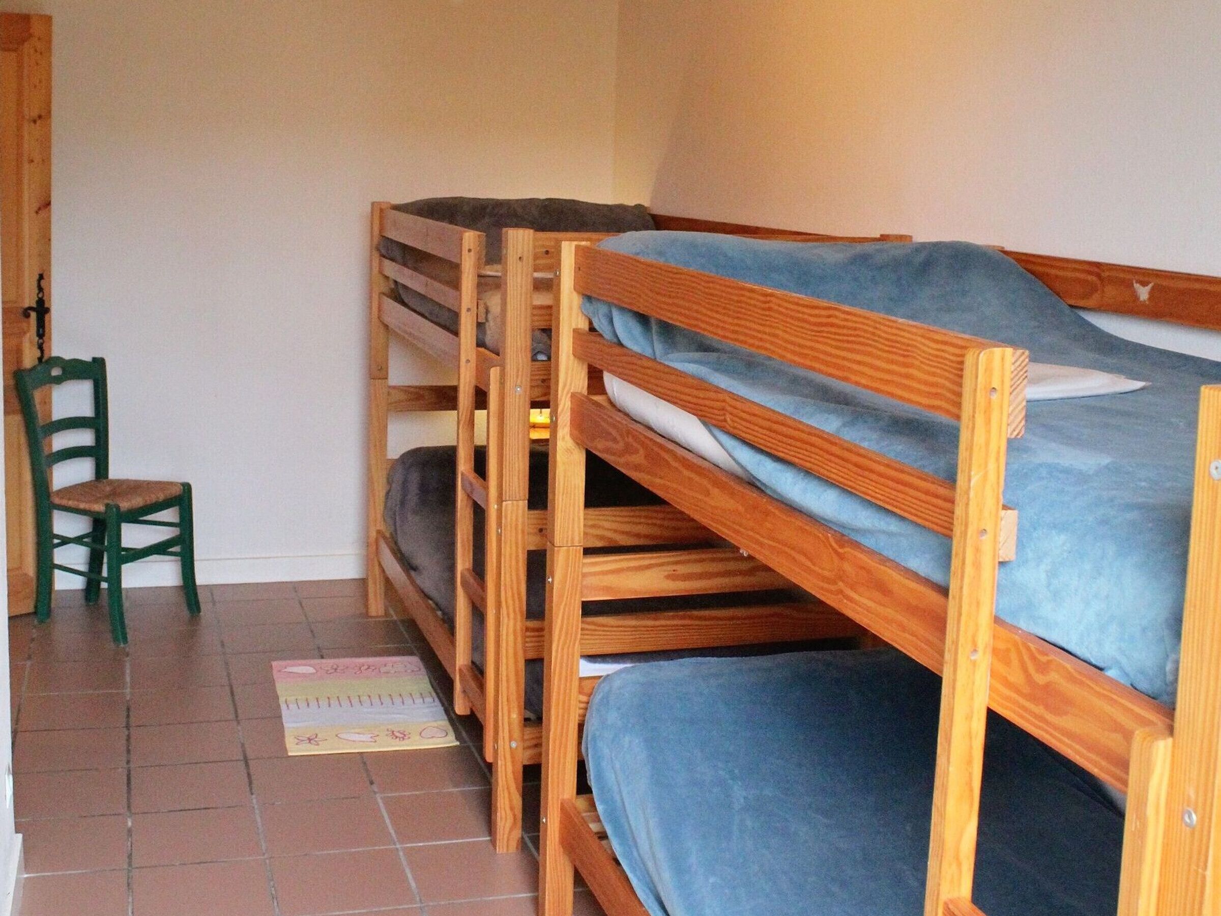 Una habitación con literas, una silla y una alfombra pequeña.