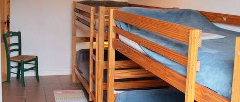 Una habitación con literas, una silla y una alfombra pequeña.