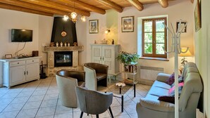 Ein Wohnzimmer mit Kamin, Sofa, Sesseln und Fernseher.