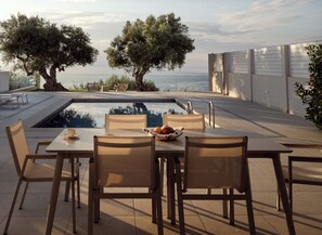 A poolside dining area with a table, chairs, and a bowl of fruit. - Villa with pool on the edge of the hill (Zakynthos)