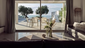 En moderne stue med en stor skydedør, der fører ud til en udendørs terrasse.