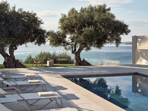 Un área junto a la piscina con sillones, una piscina y vistas al mar.