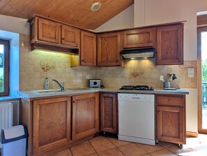 A kitchen with wooden cabinets, a dishwasher, a stove, and a window.
