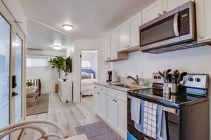A modern kitchen with white cabinetry, a built-in oven, and a microwave.