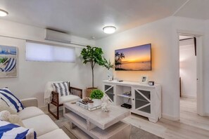A modern living room with a sofa, coffee table, and a large painting of a sunset.