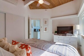 A bedroom with a bed, a television, and a ceiling fan.
