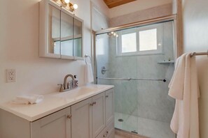 A modern bathroom with a glass-enclosed shower, a white vanity with a mirror, and a towel rack.