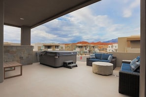 A covered outdoor area with a hot tub, seating, and a stone wall.