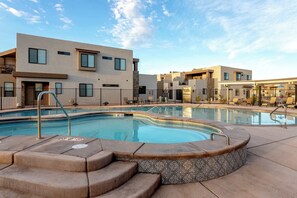 A swimming pool with steps leading into it, surrounded by a building with multiple windows and balconies. - Private Hot Tub | 5 Beds| Near Zion & Golf (Washington)