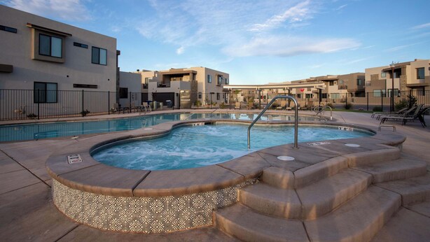 A modern hotel with a swimming pool, outdoor seating, and a stop sign.