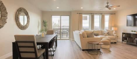 A spacious living area with a dining table, sofas, and a TV.
