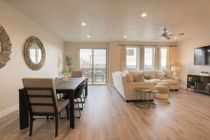 A spacious living area with a dining table, sofas, and a TV.