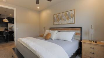 A bedroom with a bed, bedside tables, a ceiling fan, and a wall-mounted artwork.