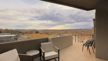 Un balcon donnant sur un paysage désertique, un canapé et deux fauteuils.