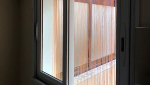 A room with two windows, one with a view of a balcony and the other with a view of a building. - Maison Place manemeur (Quiberon)