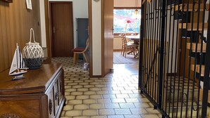 Un couloir doté d’un plancher en bois, un coin repas avec une table et des chaises, et un escalier avec une rampe en métal.
