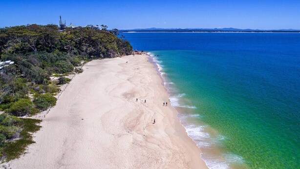 Una playa con agua turquesa cristalina y una orilla arenosa.