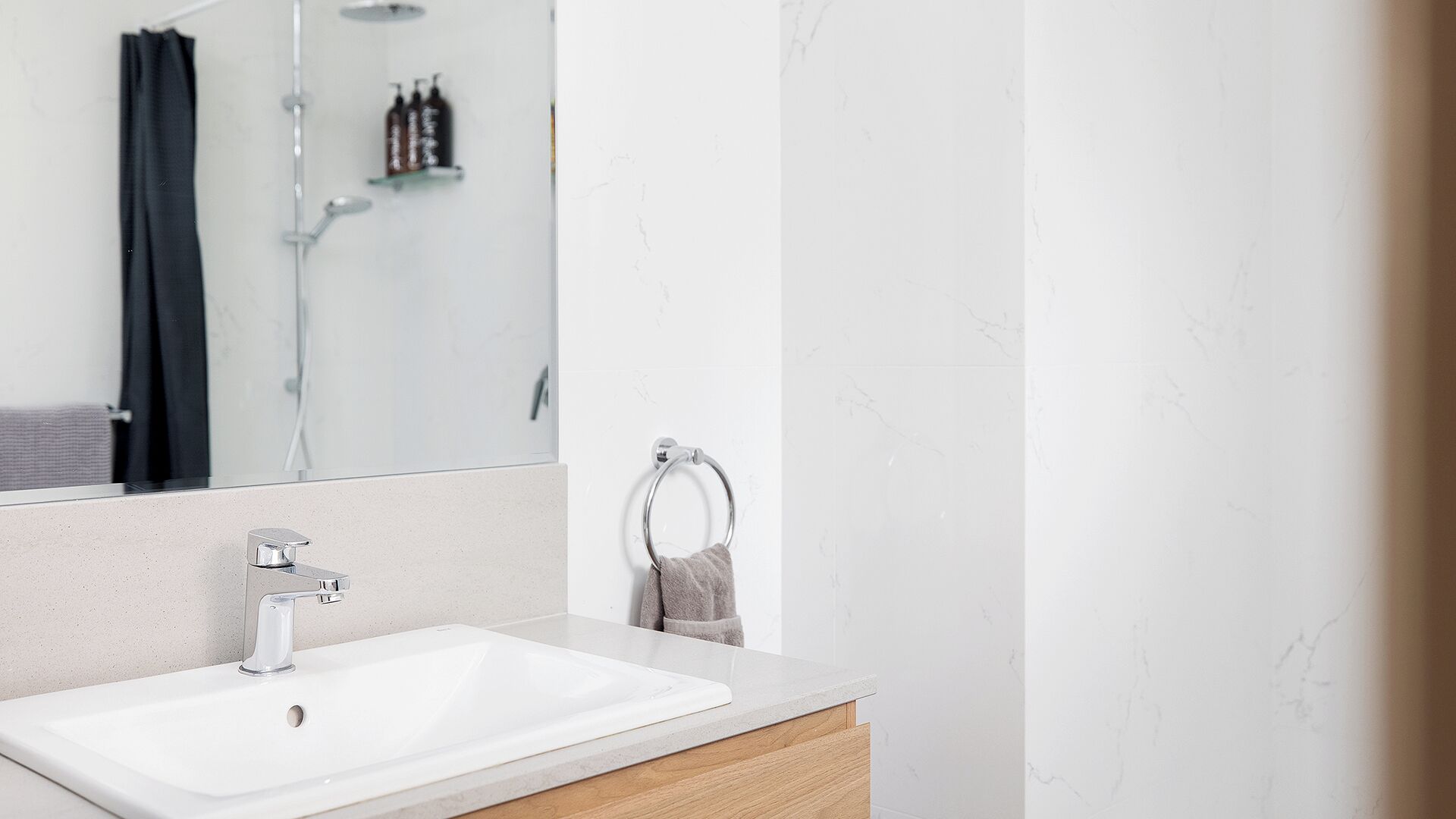 Ein modernes Badezimmer mit einem weißen Waschbecken, einem Spiegel und einem Handtuchhalter.
