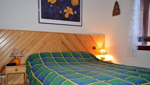 A bedroom with a wooden headboard, a bed with a blue and green checkered bedspread, a nightstand with a lamp, and a framed picture on the wall. - 2-room cabin apartment, up to 6 people, pets allowed in Bolquère (Bolquère-Pyrénées 2000)