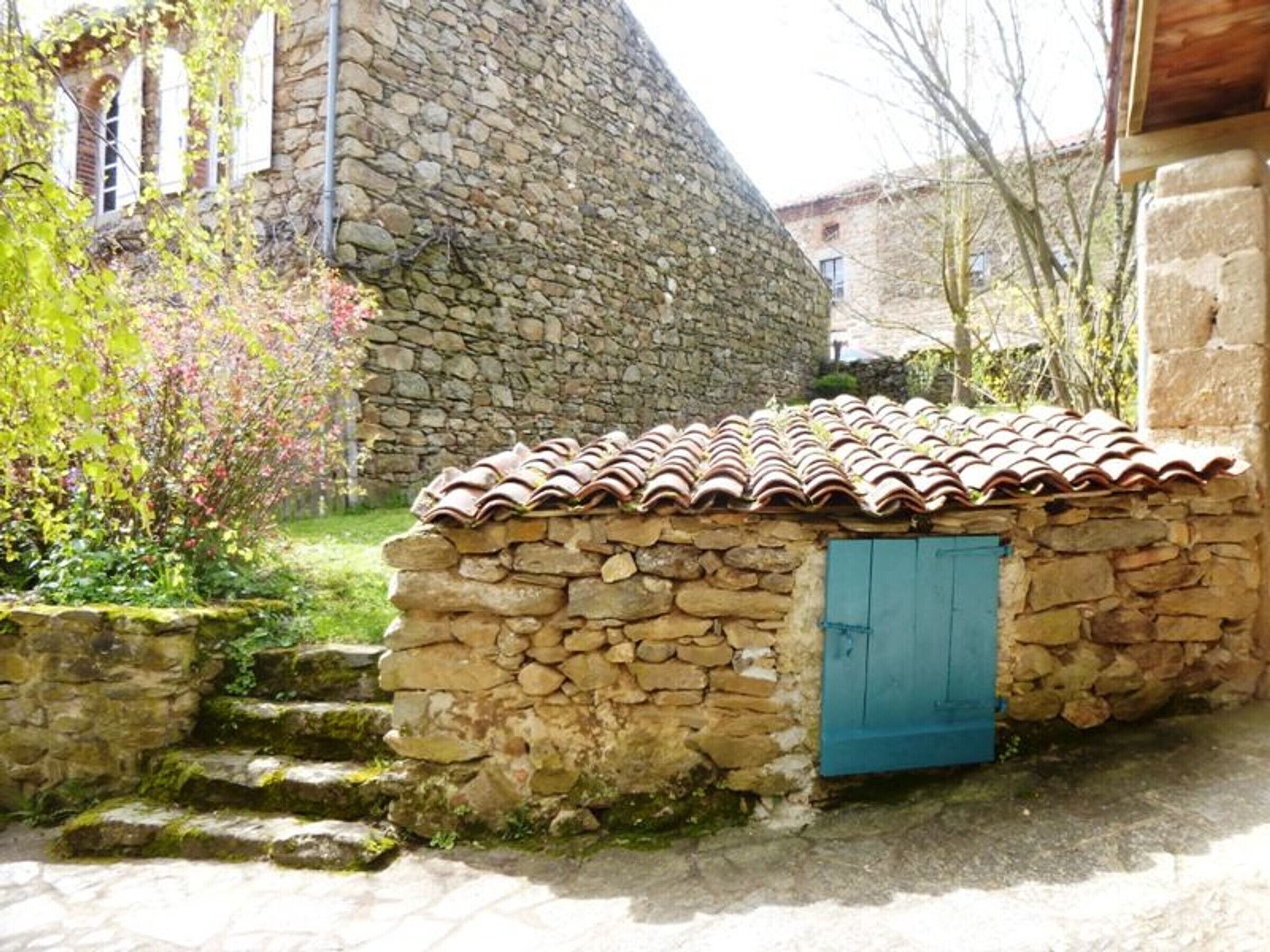 A stone building with a tiled roof and a blue door.