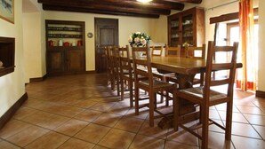 Zona pranzo con tavolo e sedie in legno, lampadario e pavimento piastrellato.