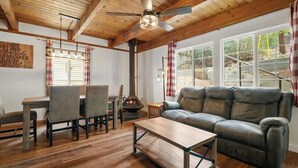 Un salon chaleureux avec un plafond en bois, un canapé en cuir, une table à manger avec des chaises et une cheminée.