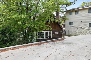 Una casa de dos pisos con un porche pequeño y una escalera que conduce al piso superior.