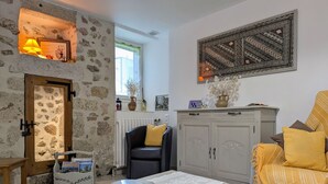 Ein gemütliches Wohnzimmer mit Steinwand, Kamin, einer schwarzen Ledersofa, einem grauen Schrank und einer gelben Decke.