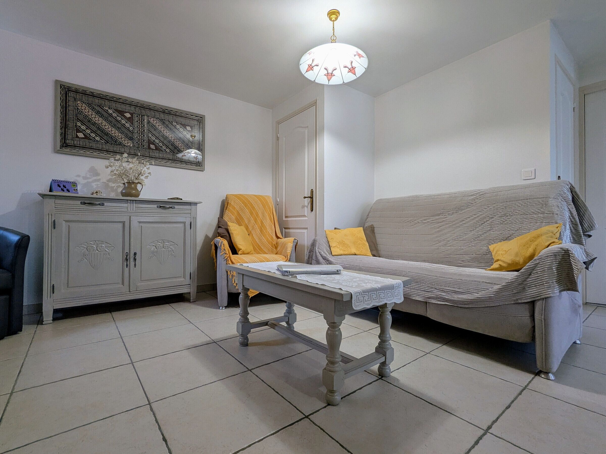 A living room with a sofa, armchair, table, and a cabinet.