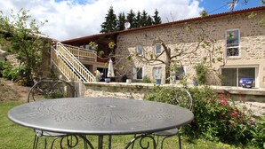Ein Gebäude aus Stein mit rotem Dach, einer Treppe und einem Garten mit einem Metalltisch und -stühlen.