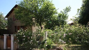 Uma casa com jardim, um portão de madeira e uma cerca.