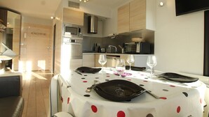 A modern kitchen with a dining table set for two, equipped with a microwave, oven, and toaster.