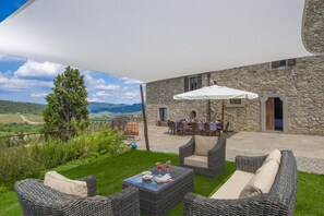 An outdoor patio with wicker furniture, a dining table, and a white umbrella. - AMORE RENTALS - Villa Bellaflore with 3 Private Pools, Garden, Terraces and Parking (Panzano)