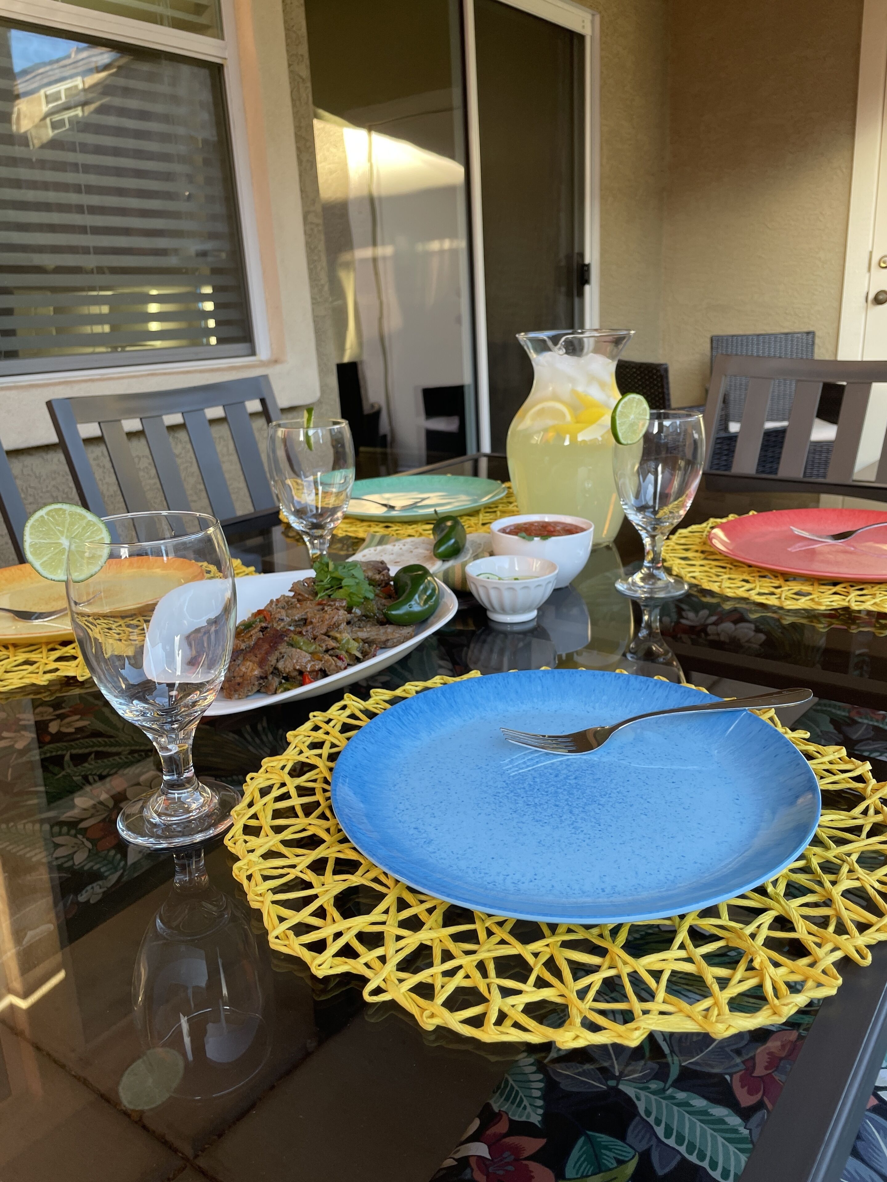 A dining table set with plates, glasses, and a pitcher of lemonade.