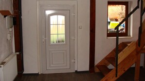 A room with a white door, a window with a view, and a wooden staircase. - Cottage Hühnerstall (Zülpich)