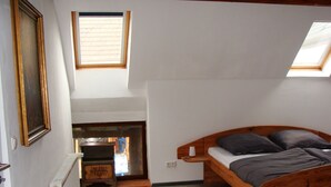 A bedroom with a wooden bed, a radiator, a window, and a painting on the wall. - Cottage Hühnerstall (Zülpich)