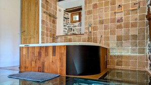 A modern bathroom with a glass-enclosed bathtub, wooden vanity, and stone-tiled walls. - Luxury Gîte with Spa, Terrace, and Game Room in Scenic Blanlhac, Rosières (Rosières)