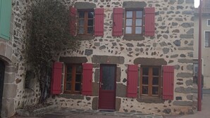 Un bâtiment en pierre avec une porte et des volets rouges, portant le numéro 56.