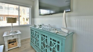 A room with a teal cabinet, a small white table with a lamp, and a large mirror on the wall.