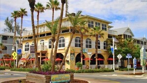 A multi-story hotel with balconies, palm trees, and outdoor seating areas.