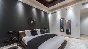 Ein modernes Schlafzimmer mit einem großen Bett, einem runden Spiegel und einem Nachttisch mit Lampe.
