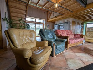 Ein großzügiger Wohnbereich mit Ledersofas, Holzboden und einer sichtbaren Küchenzeile.