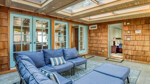 Un intérieur moderne avec un mur en bois, un canapé bleu et une porte en verre donnant sur une autre pièce.