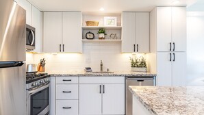 Une cuisine moderne avec des armoires blanches, des appareils en acier inoxydable et un comptoir en granit.
